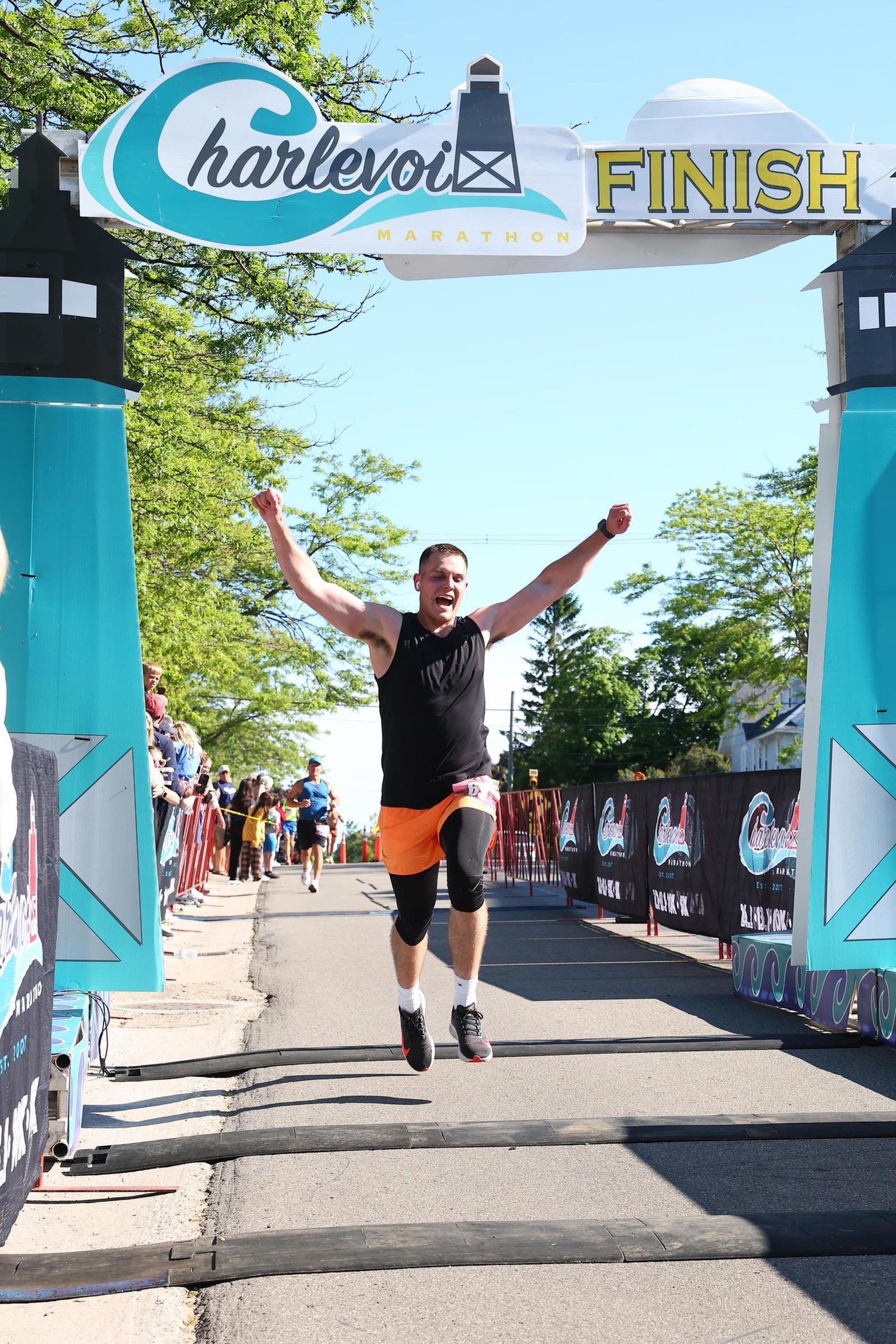 Person celebrating at a finish line with 'Charlevoix Finish' sign in the background