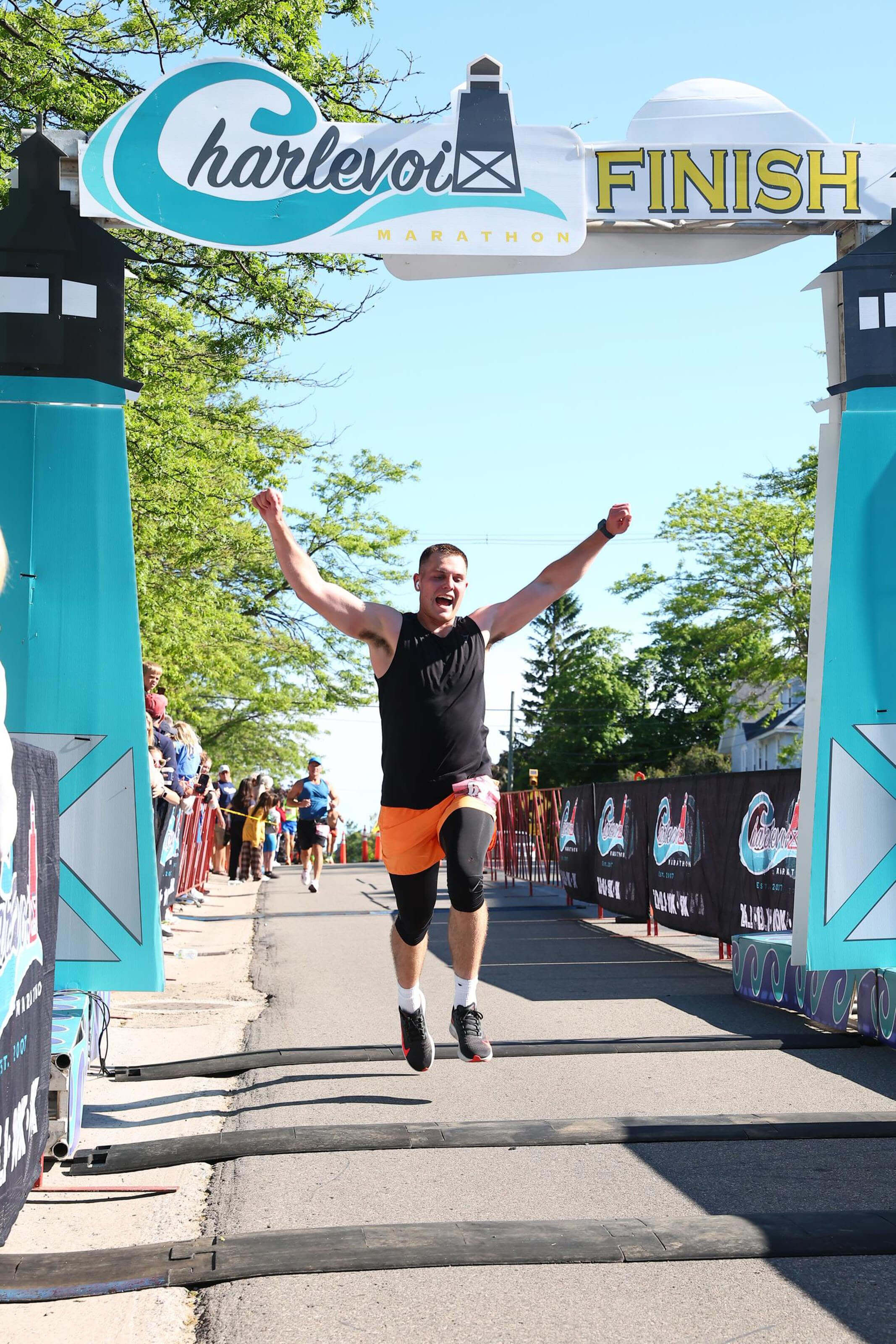 Person celebrating at a finish line with 'Charlevoix Finish' sign in the background