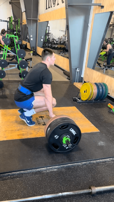 Person lifting a barbell with weights in a gym setting