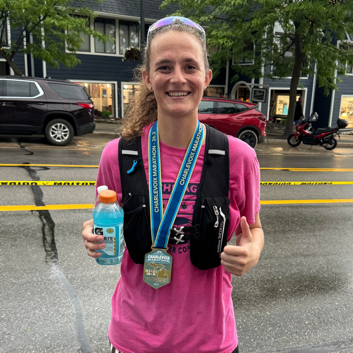 Runner in pink shirt with hydration pack and water bottle on a street