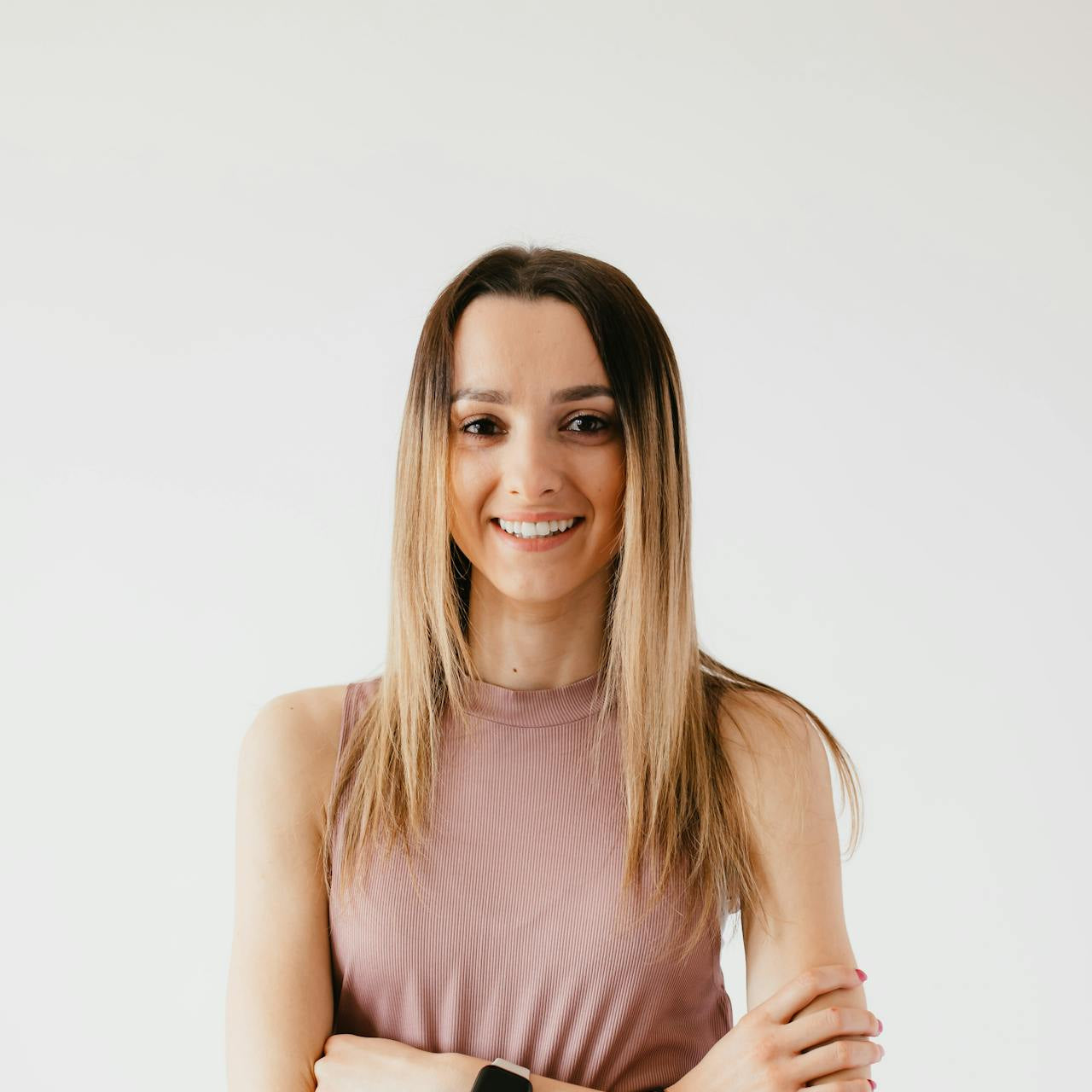 Woman wearing a pink sleeveless top and black leggings with a white background